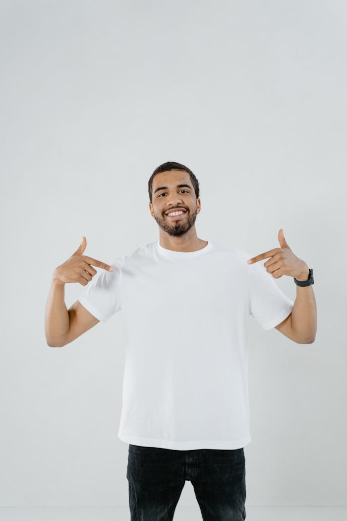 Confident man smiling and pointing at his white shirt with copy space.